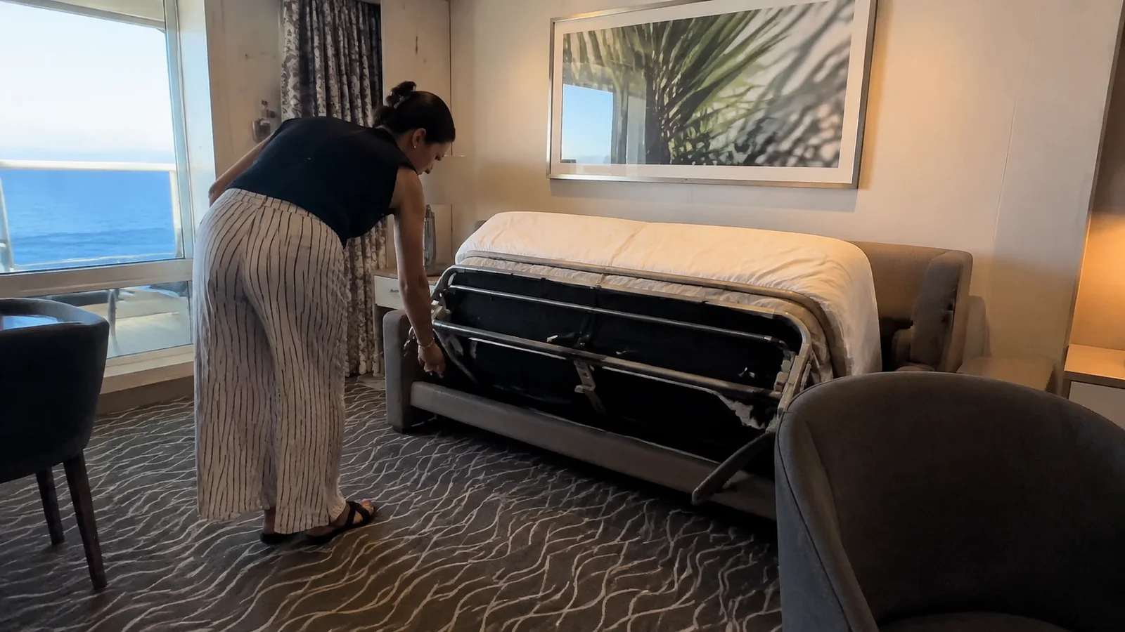 Passenger unfolding a sofa bed in a cruise suite.