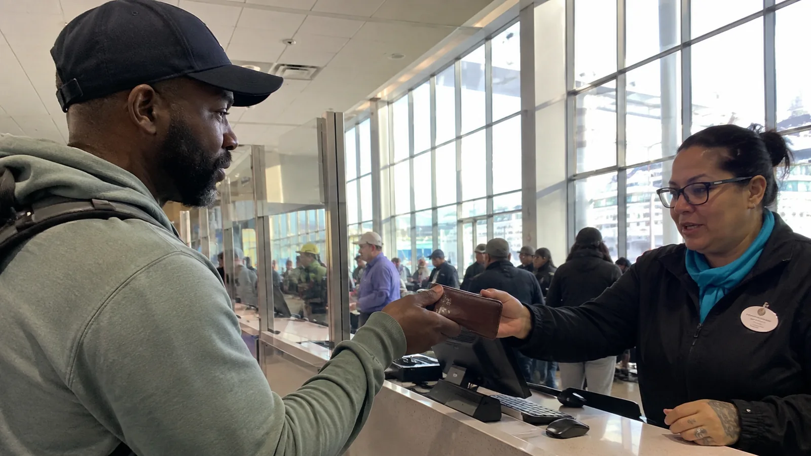Terminal staff member checking a traveler's document wallet at a counter.