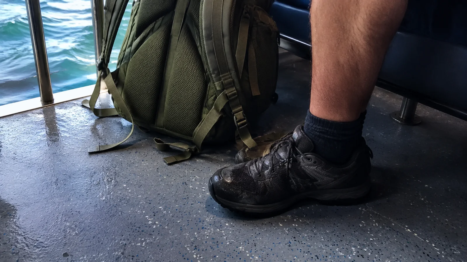 Hiking shoes and backpack on the floor of a passenger boat.