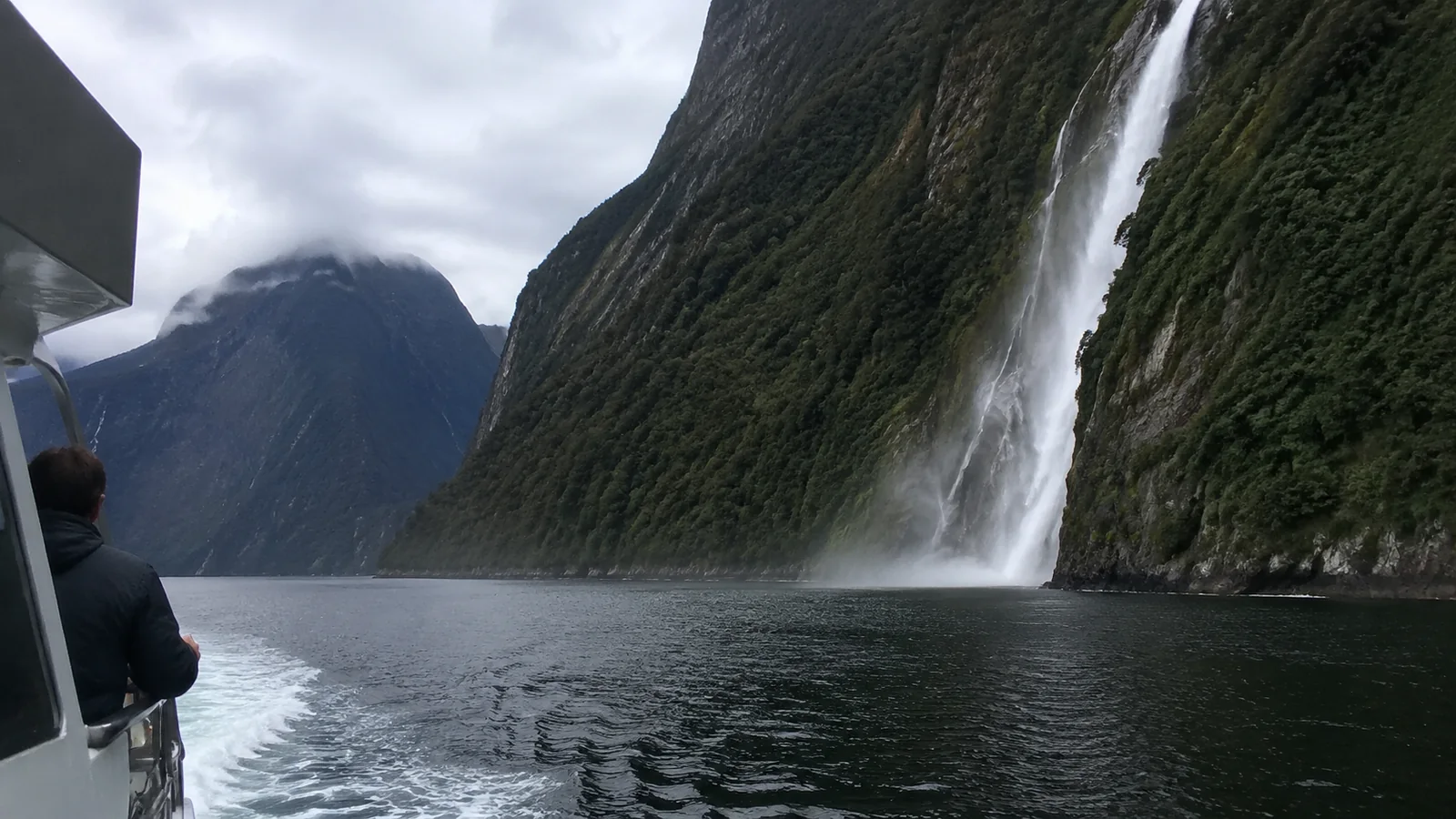 Waterfall beside a fjord viewed from a boat deck