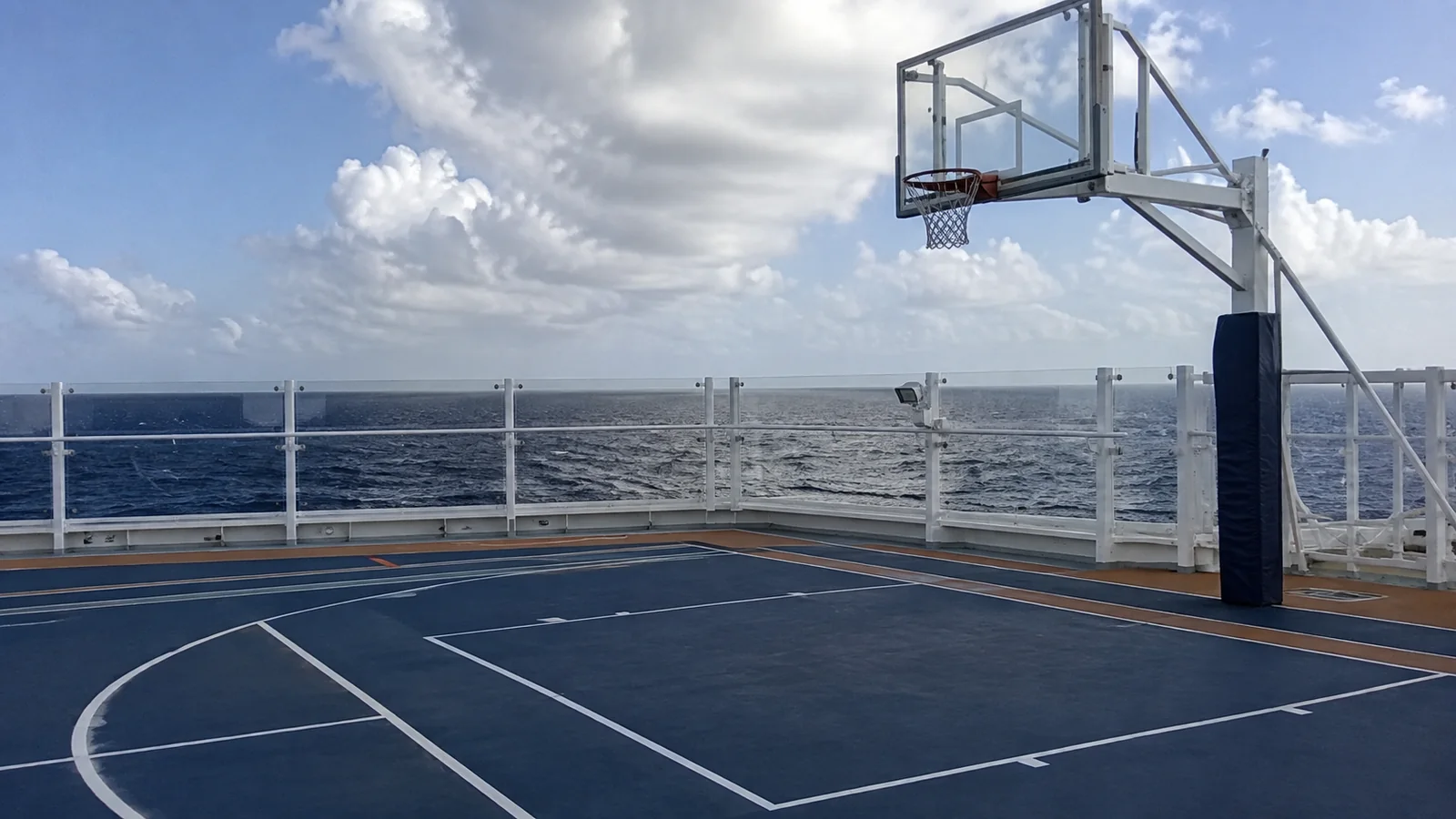Empty basketball court on a ship deck overlooking the ocean.