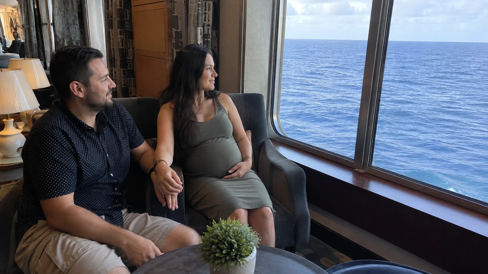 Couple seated together beside a large ocean-facing lounge window.