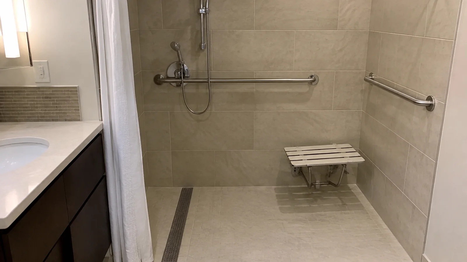 Accessible bathroom shower with grab bars and a folding seat.