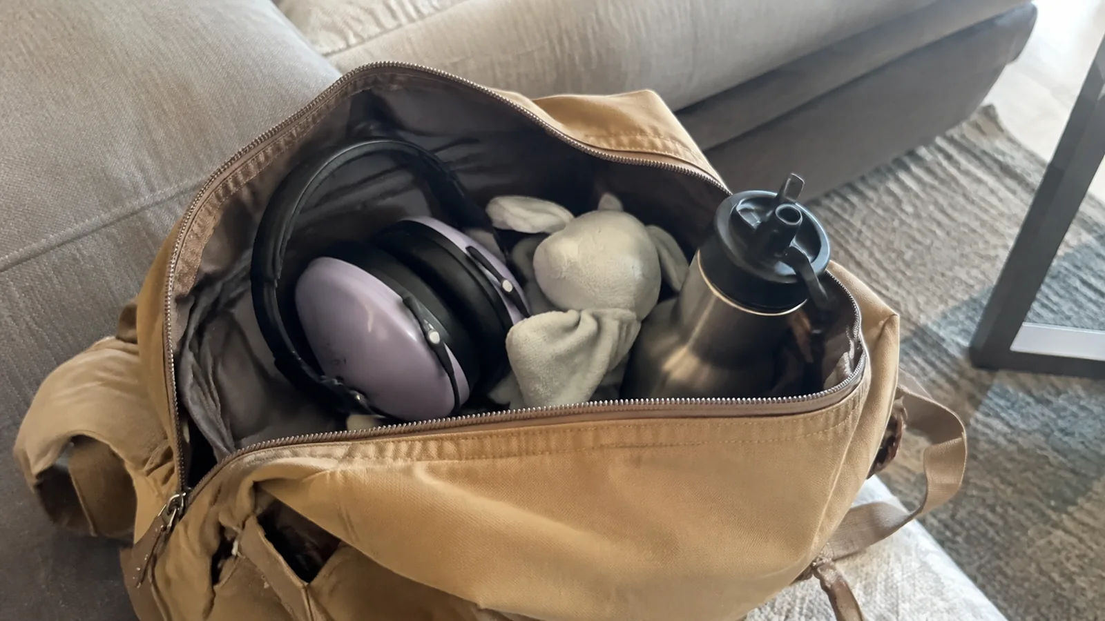 Headphones, plush toy, and water bottle packed inside an open bag.