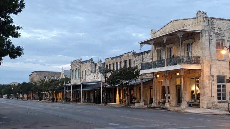 Quiet main street lined with historic stone storefronts and covered balconies.