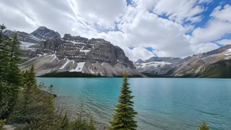 Turquoise alpine lake below snow-streaked rocky mountain peaks.