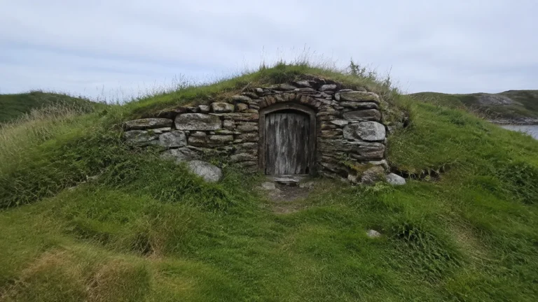 Low stone cellar with a wooden door built into a grassy mound.