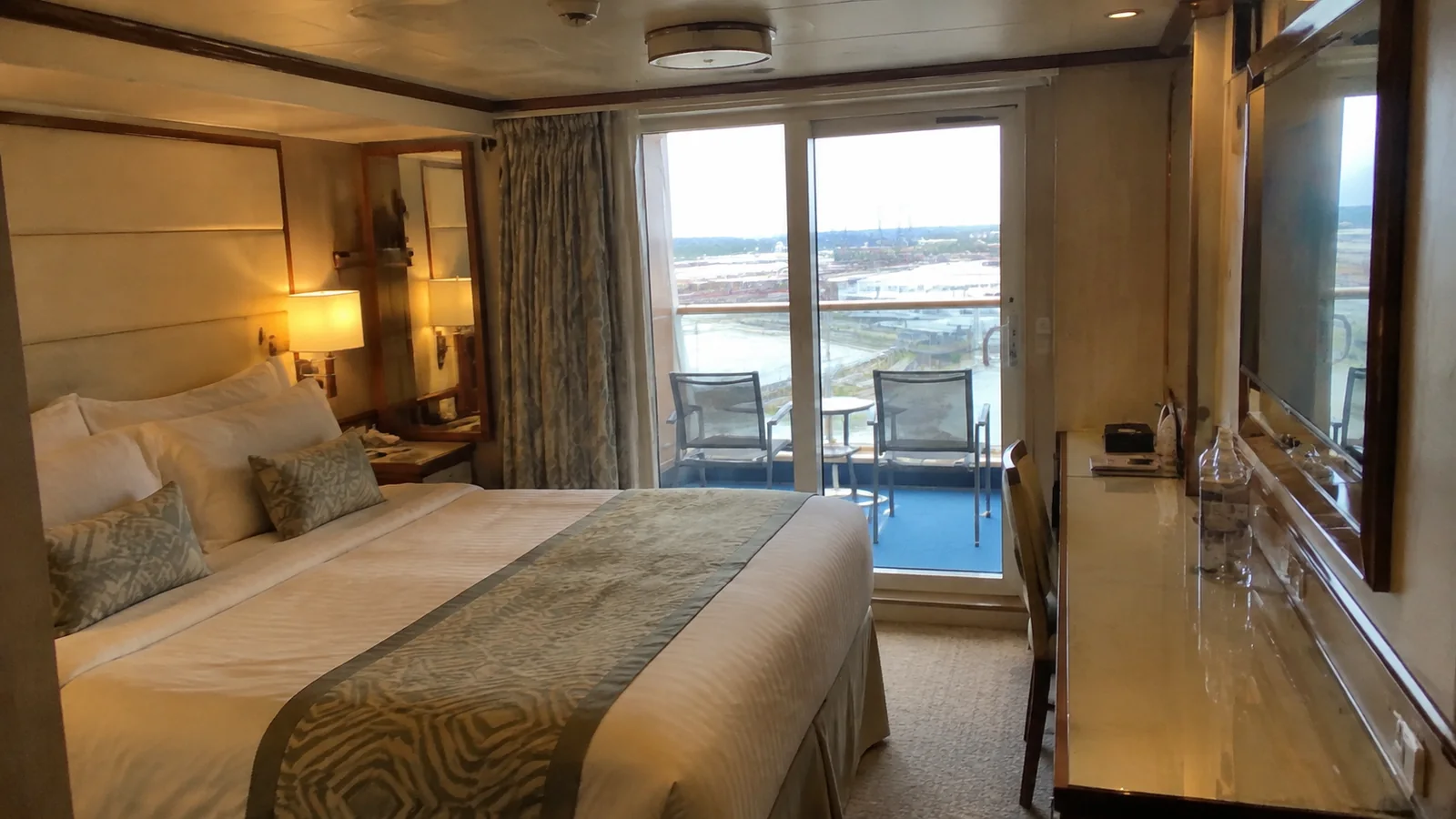 Balcony cabin with a double bed and two chairs outside.