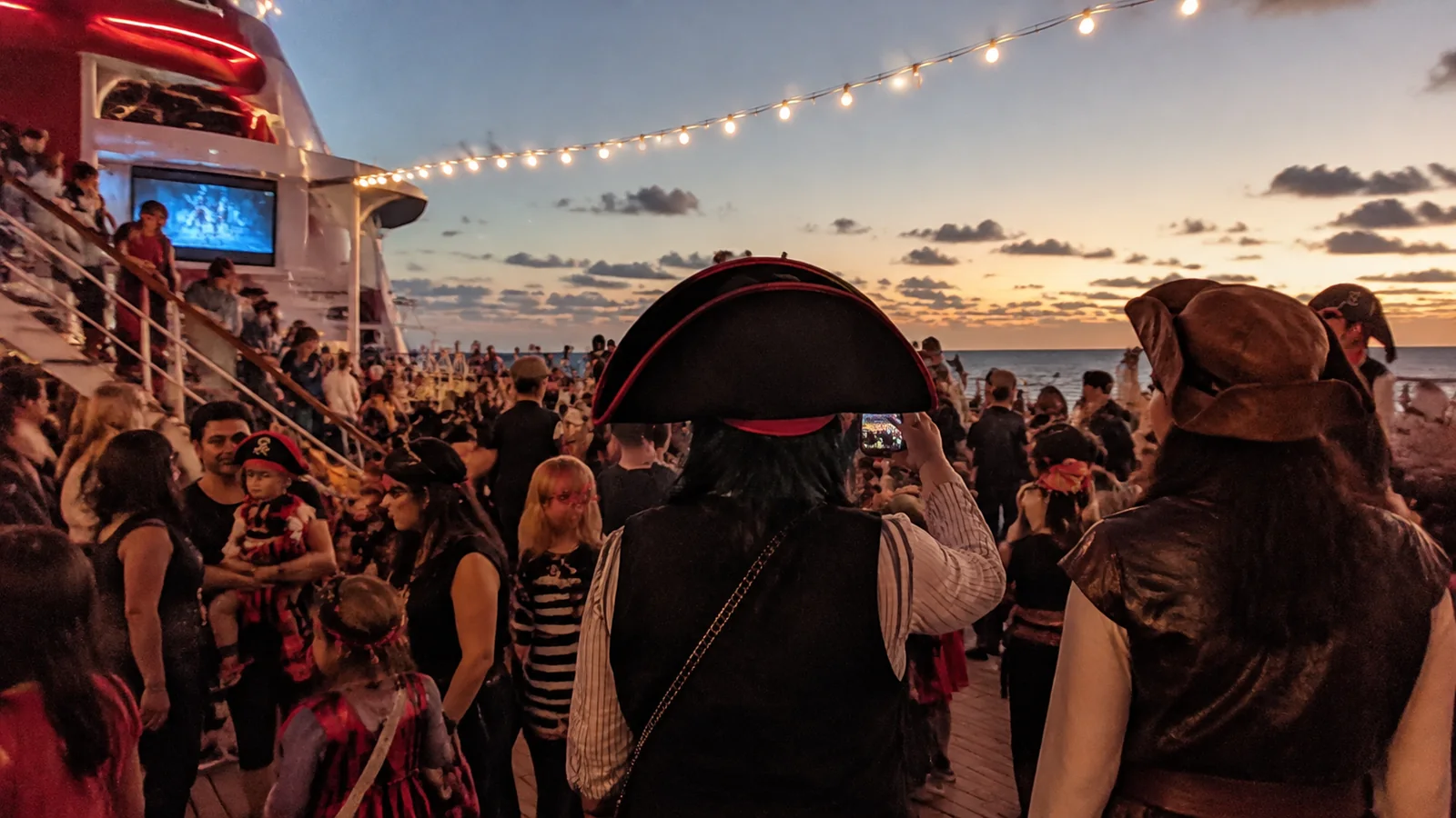 Families wearing pirate-inspired outfits at an evening cruise deck party.