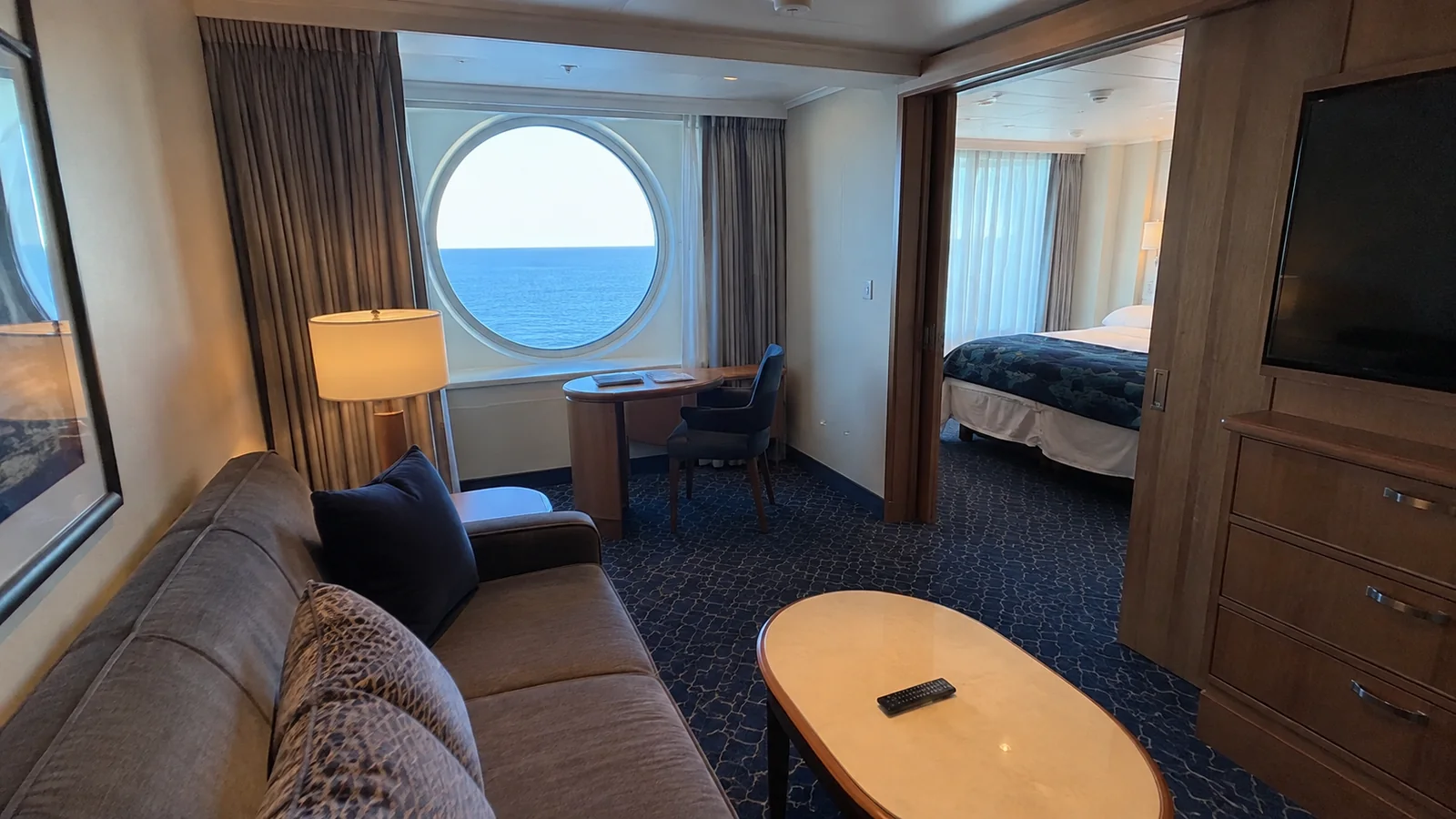 Separate sitting area has a sofa and round ocean window.