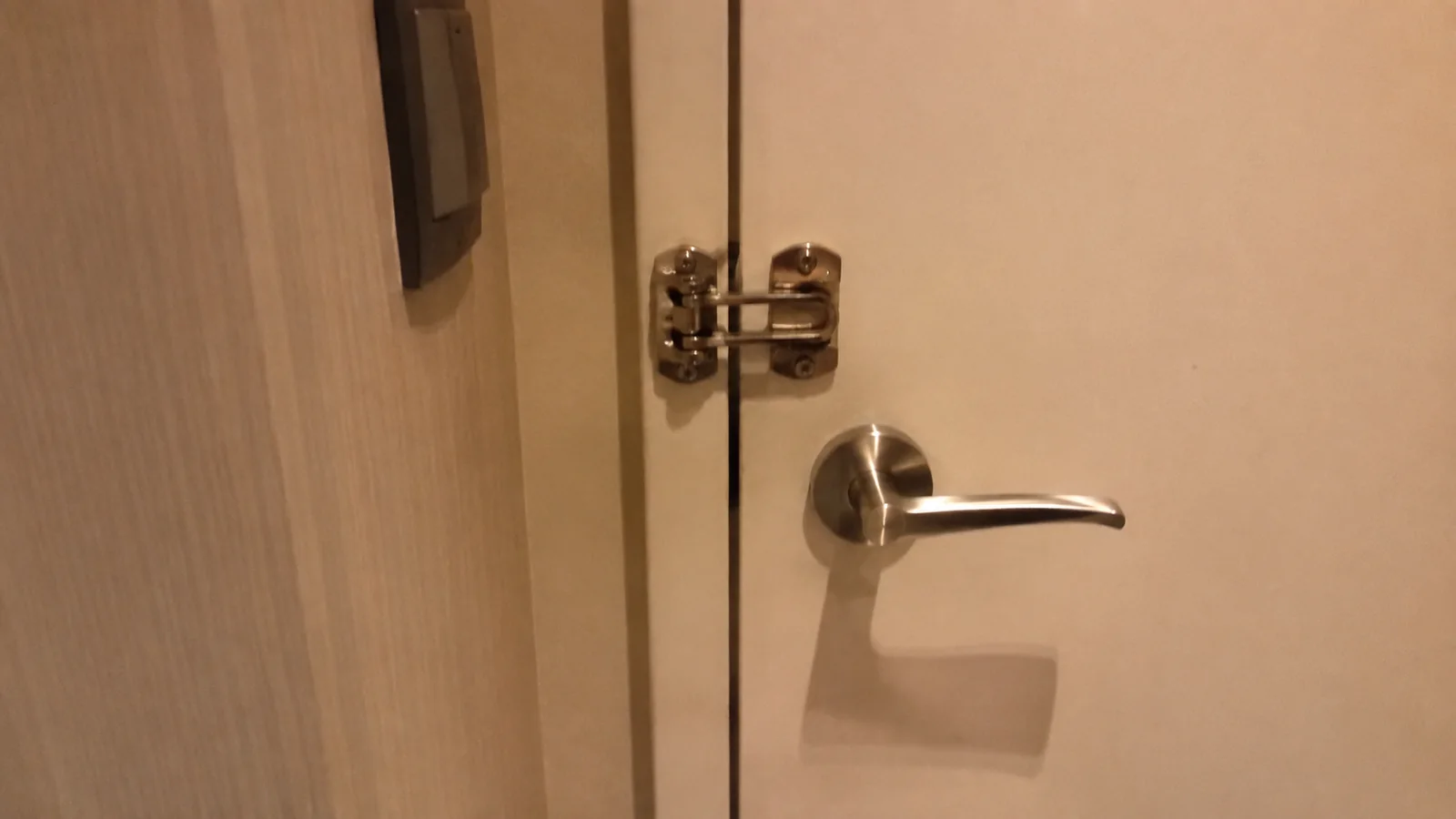 Close view of a swing-bar door latch and silver lever handle.