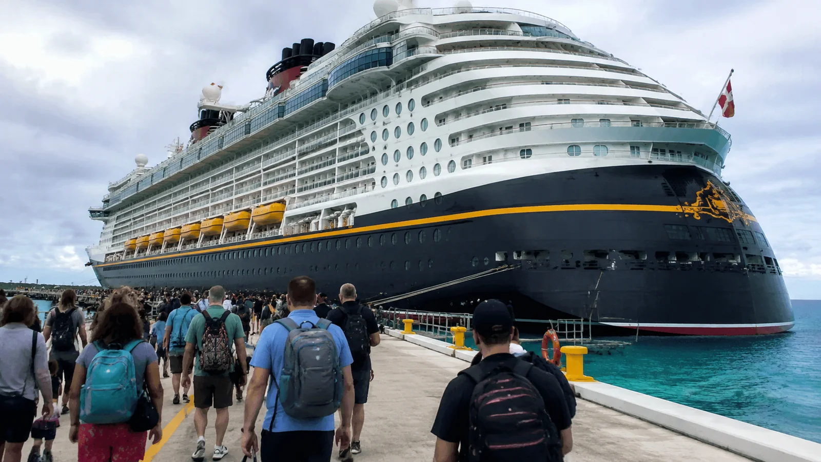 Large cruise ship docked as passengers walk toward it