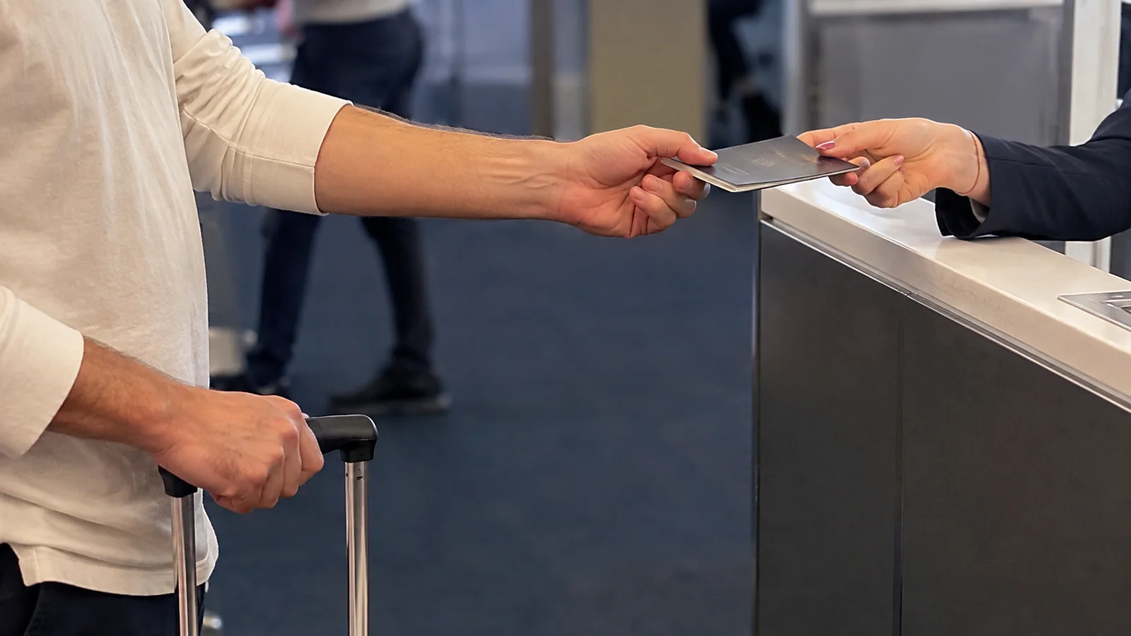 Traveler handing a passport across a terminal check-in counter.