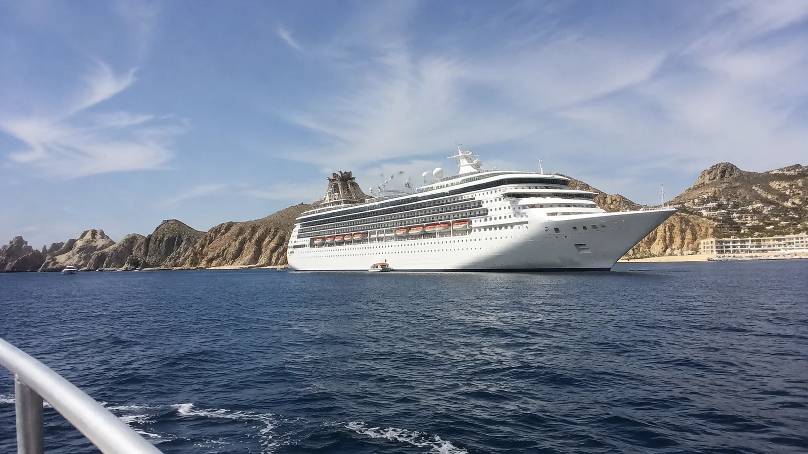 Cruise ship anchored near a dry rocky coastline.