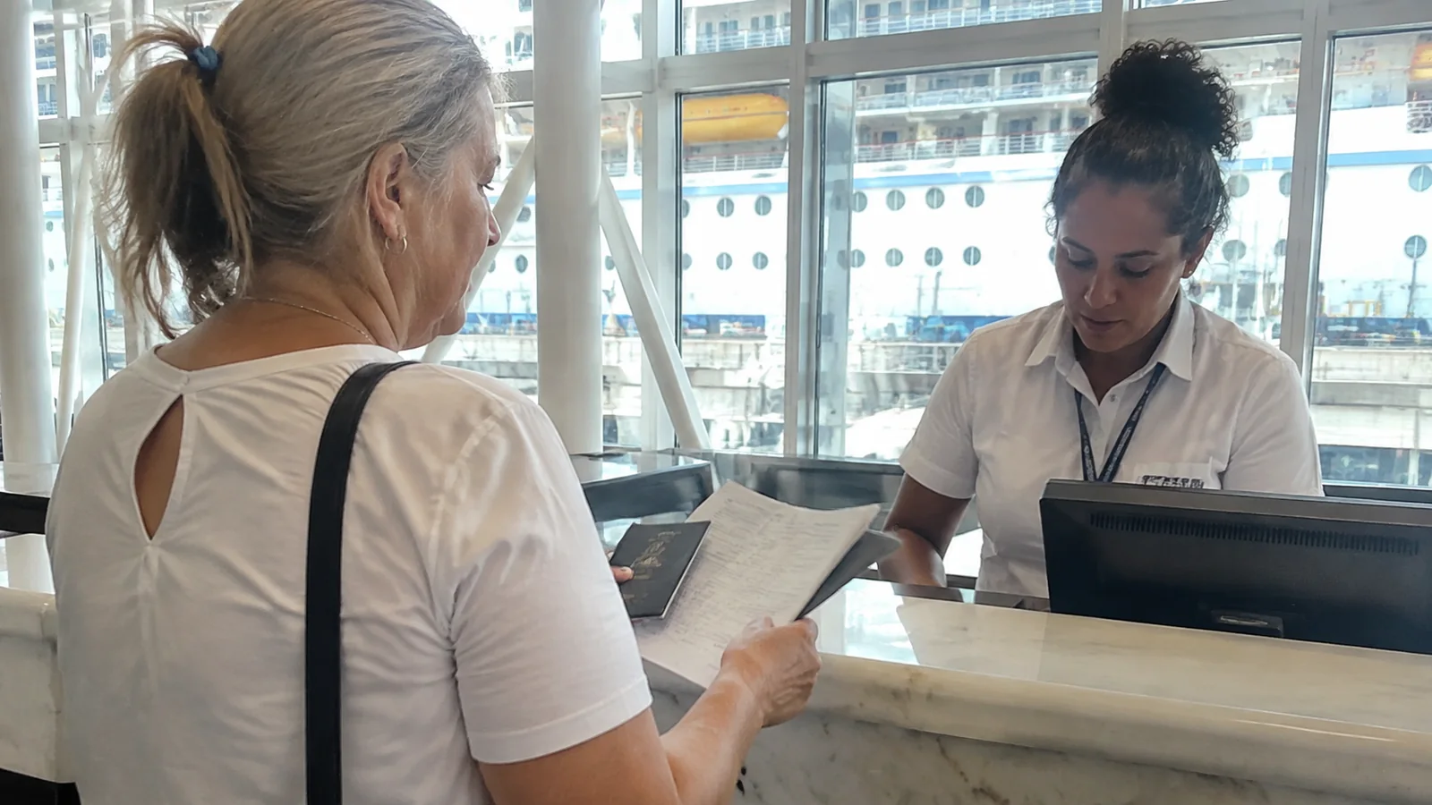 Passenger presenting paperwork to a terminal check-in agent.