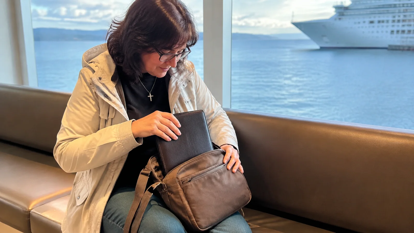 Traveler securing a document wallet inside a handbag.