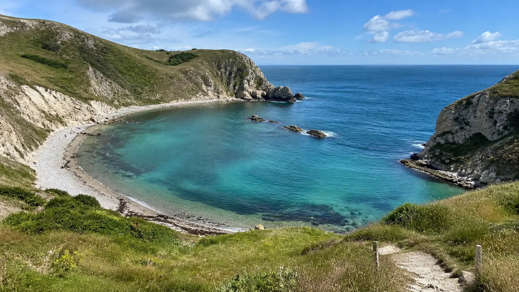Curving shoreline and turquoise water at Lulworth Cove in Dorset.