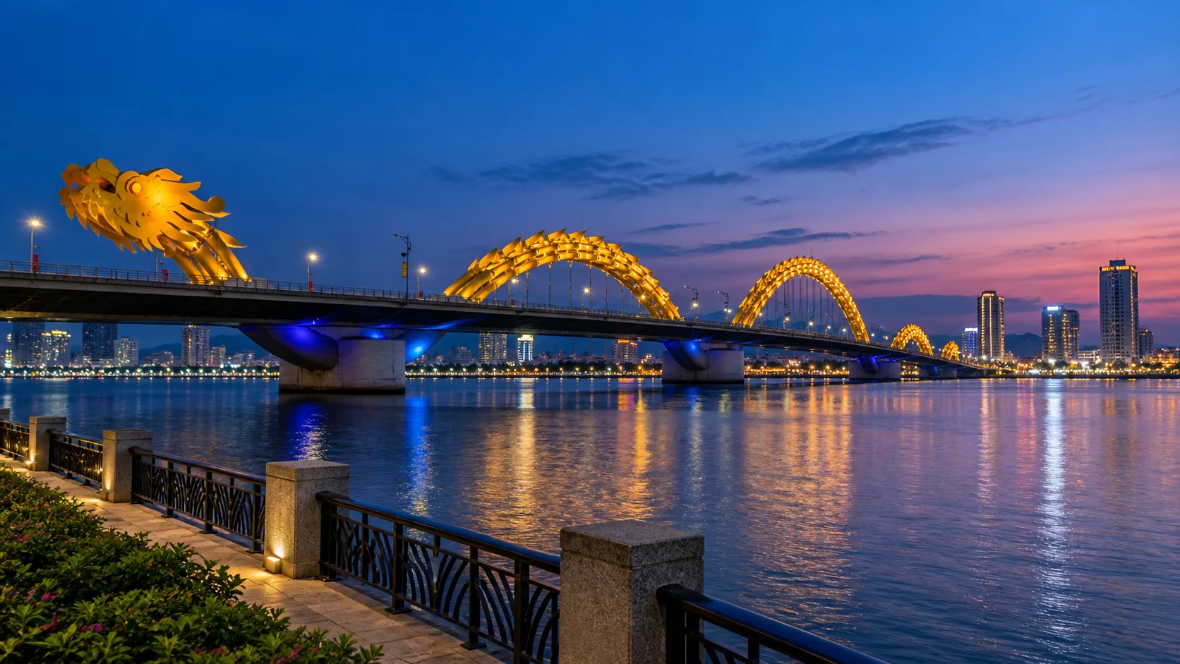 Da Nang's yellow Dragon Bridge glowing above the Han River and city reflections at blue hour.