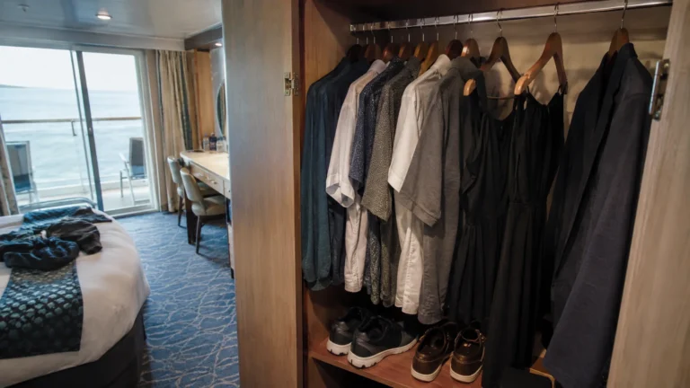Shirts, dresses and jackets hanging in a cruise cabin wardrobe.