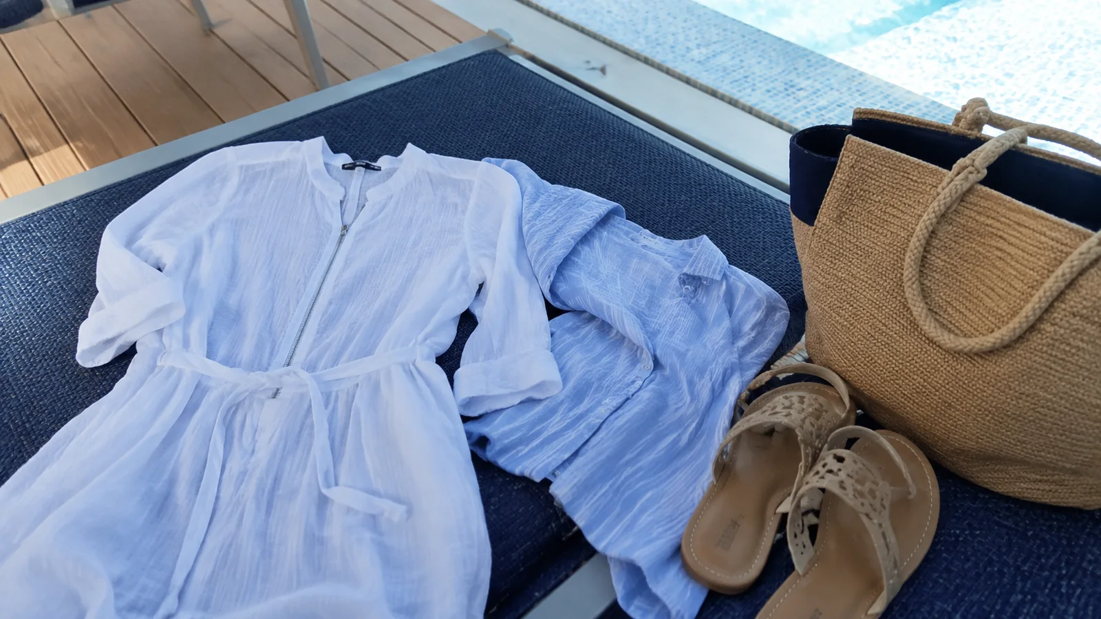 Light dress, blue shirt, sandals and a tote bag on a deck chair.