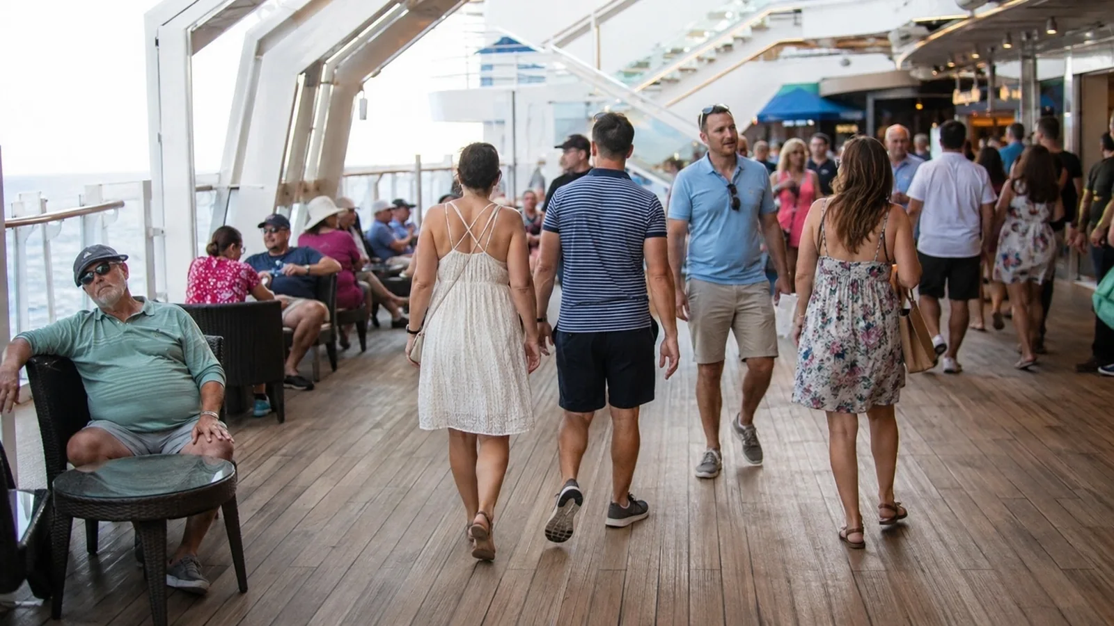 Passengers in casual clothes walking along a busy covered promenade.