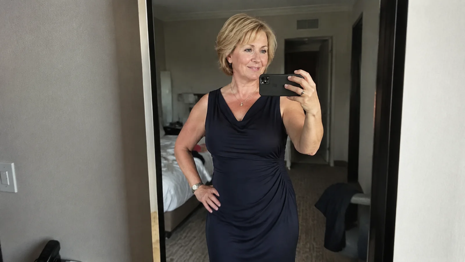 Woman taking a mirror selfie while wearing a navy evening dress