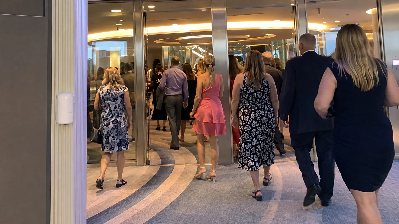 Formally dressed passengers walking through an illuminated cruise ship interior