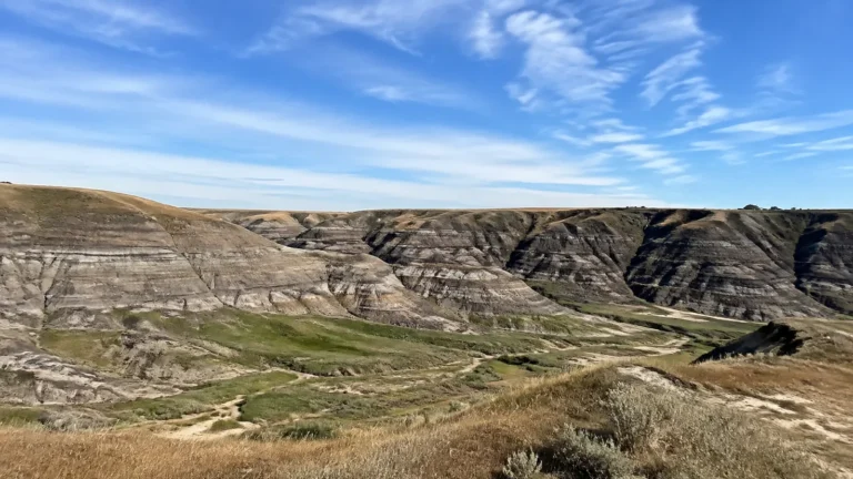 Layered badlands hills surround a winding green valley.