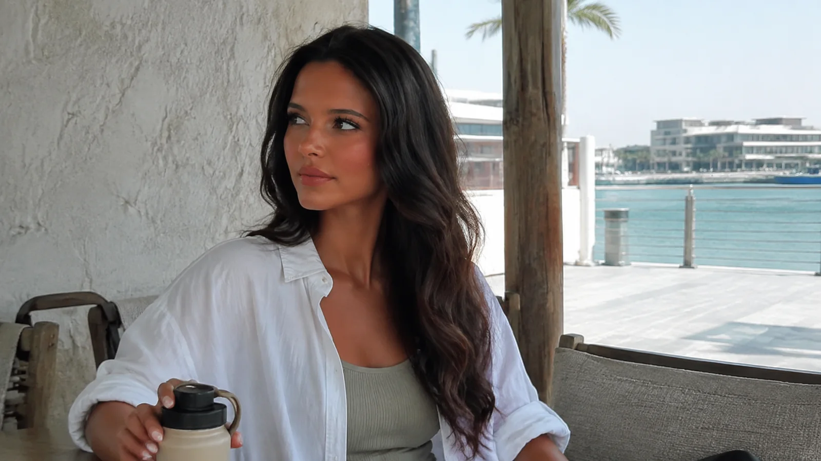 Woman holding a takeaway coffee in a waterfront cafe.