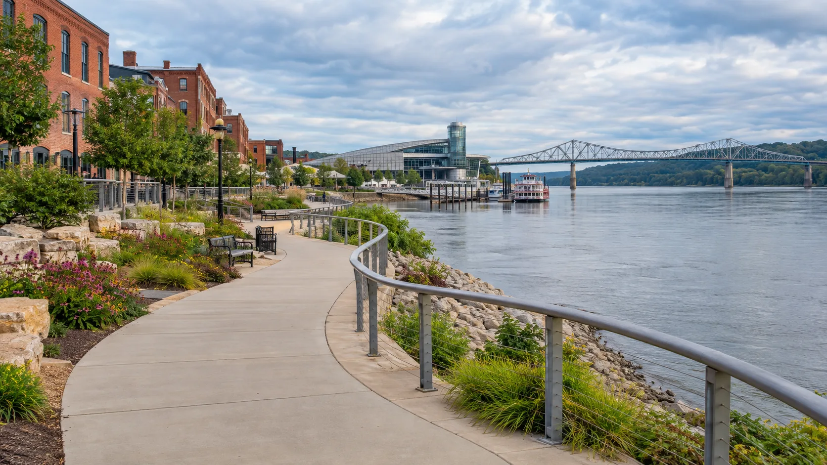 A landscaped riverwalk curves past brick heritage buildings at the Port of Dubuque.