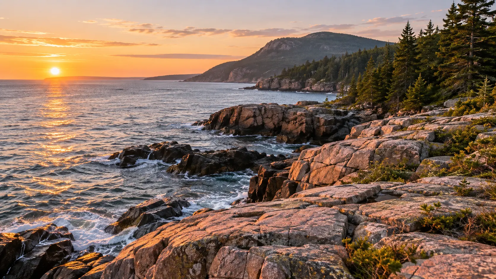 Rocky Atlantic shoreline and evergreen-covered mountains at Acadia National Park in Maine.