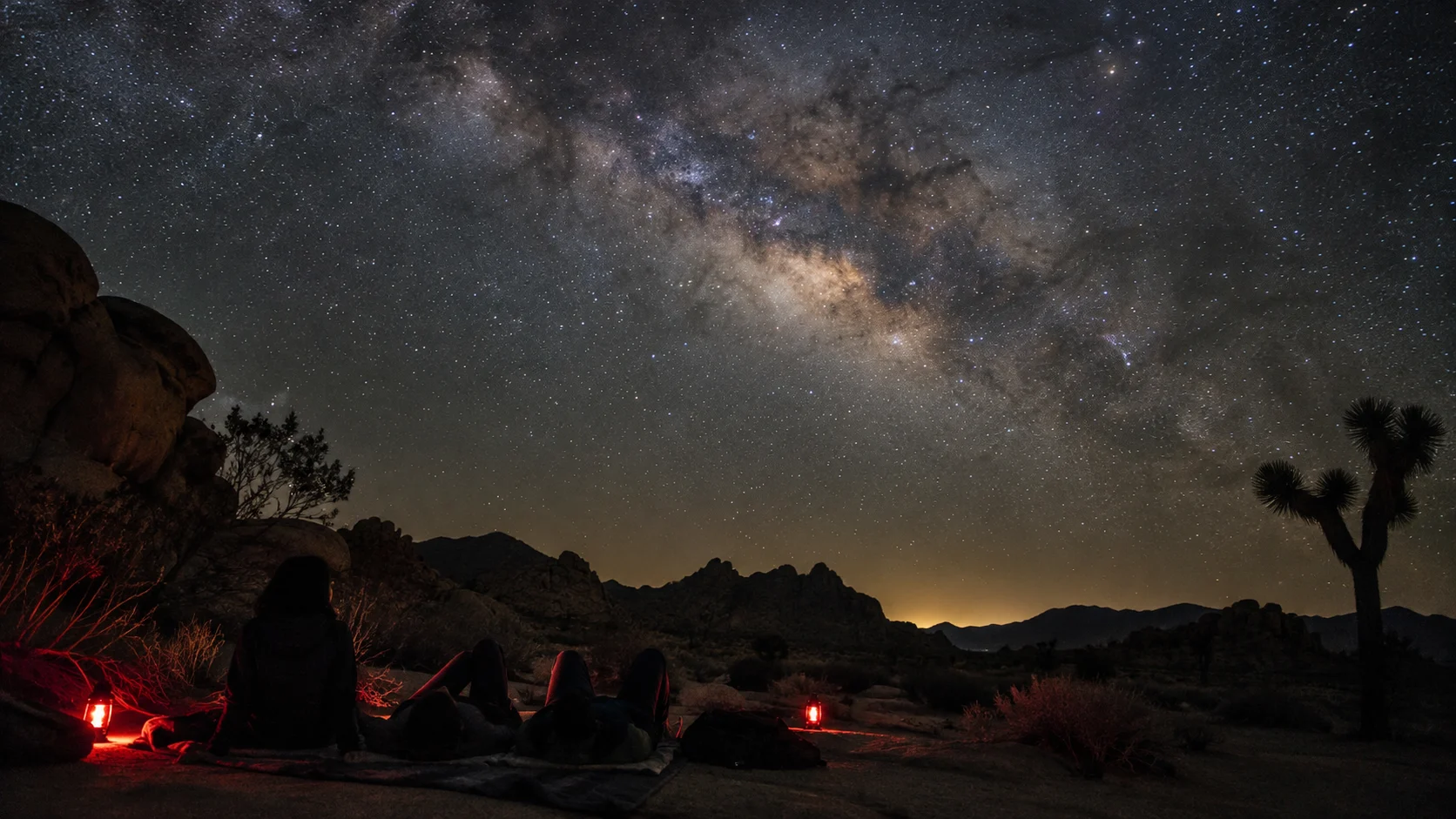 Travelers stargazing beneath the Milky Way in a dark-sky desert landscape