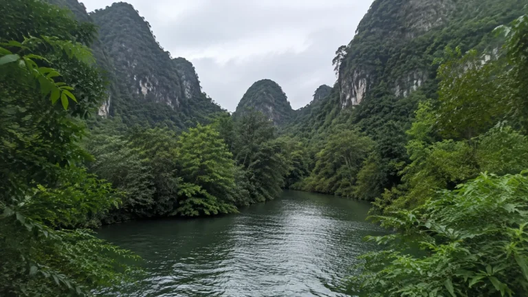 River winds between steep limestone hills covered in dense greenery.