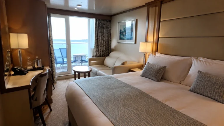 Balcony cabin with a double bed, sofa and small table.