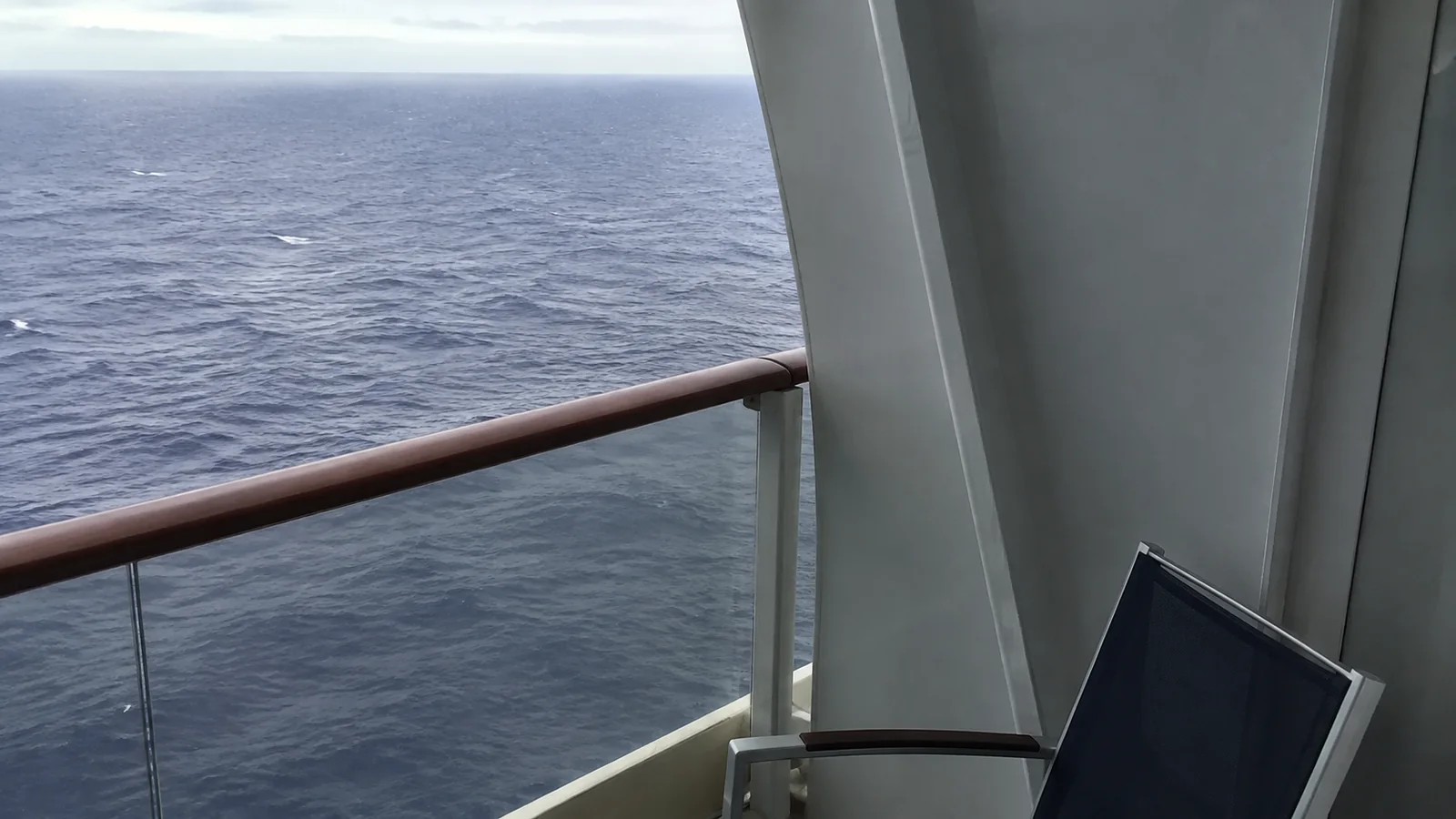 Small ship balcony with a chair and an open ocean view.