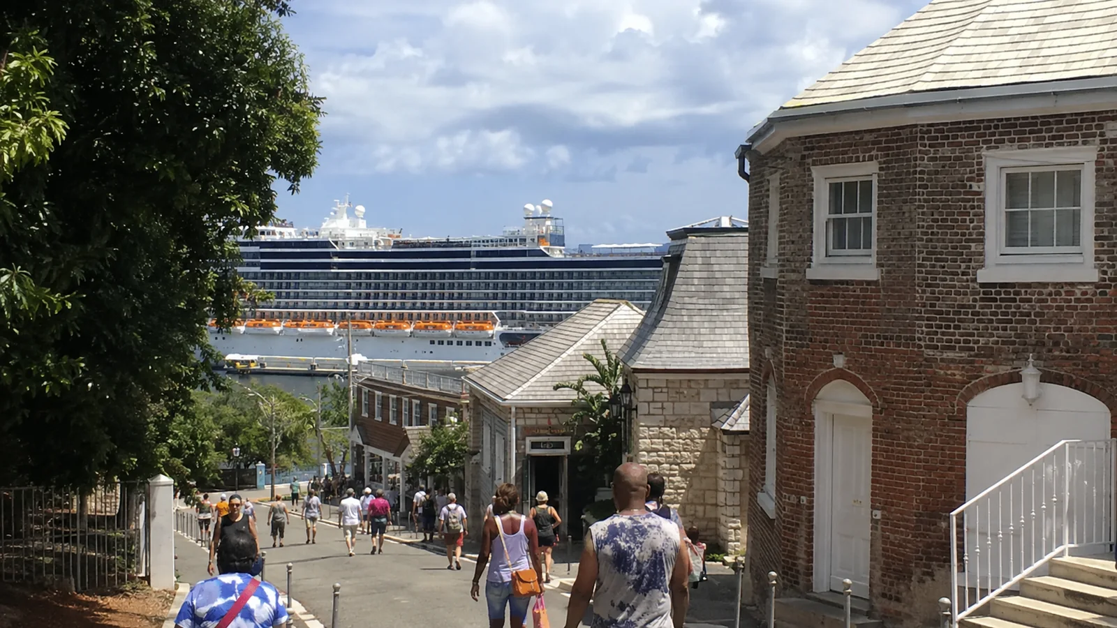 Cruise passengers walking through a port complex toward a docked ship.
