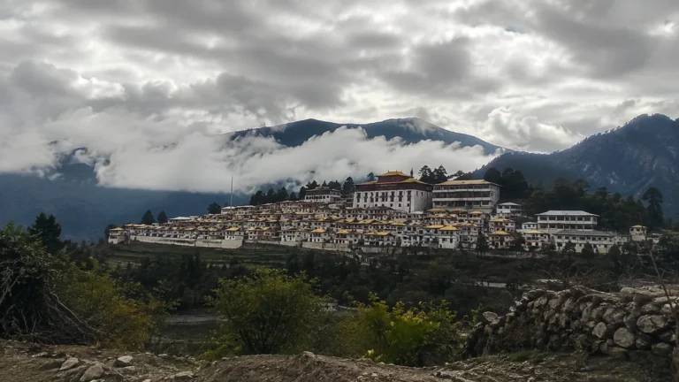 Large hillside monastery complex beneath mist-covered mountain slopes.