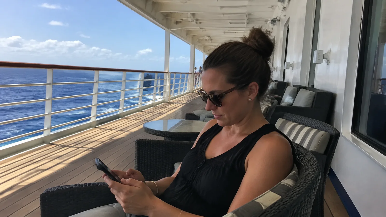 Passenger using a phone while seated on a covered deck.
