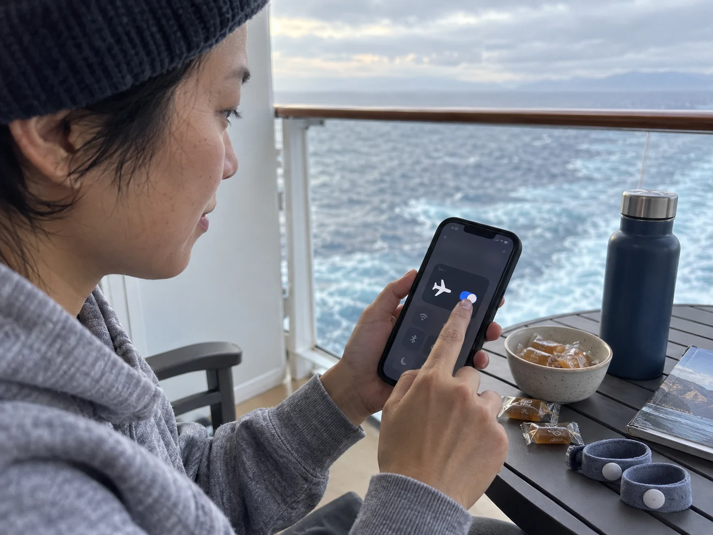 A cruiser switches a phone to airplane mode beside seasickness remedies.