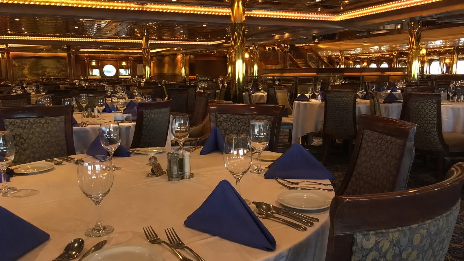 Elegant cruise ship dining room with white tablecloths and folded blue napkins
