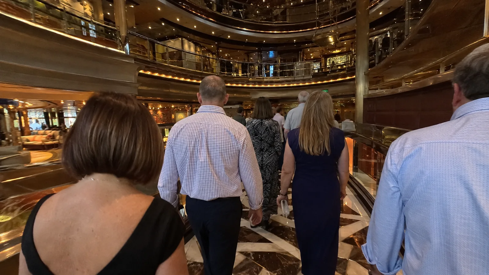Passengers in evening clothes walking through an ornate cruise ship atrium