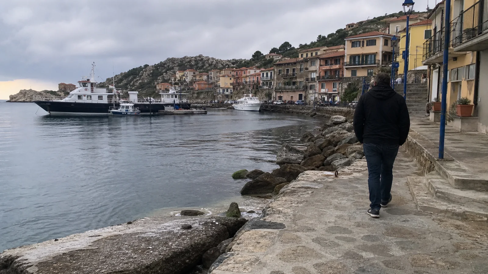 Person walking along a stone waterfront beside colorful buildings