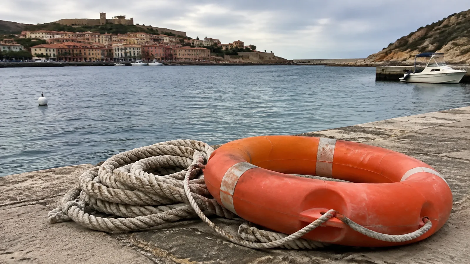 Orange life ring and coiled rope on a harbor quay