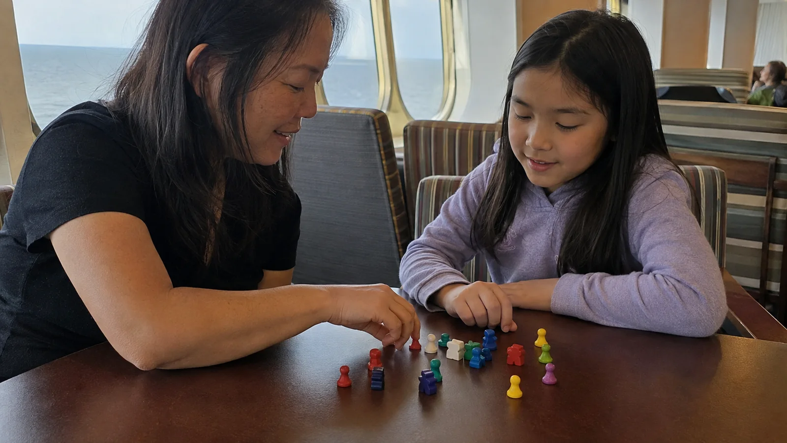 Woman and child arrange colorful game pieces on a table.
