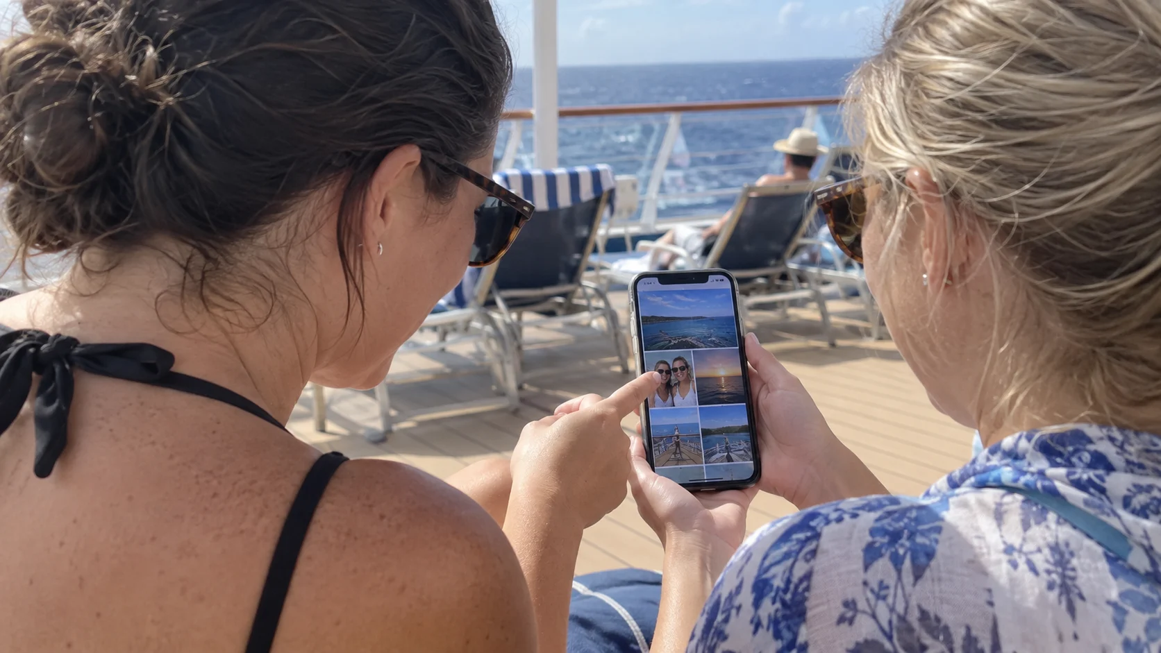 Two friends reviewing a shared collection of cruise photo prompts and pictures on a phone.