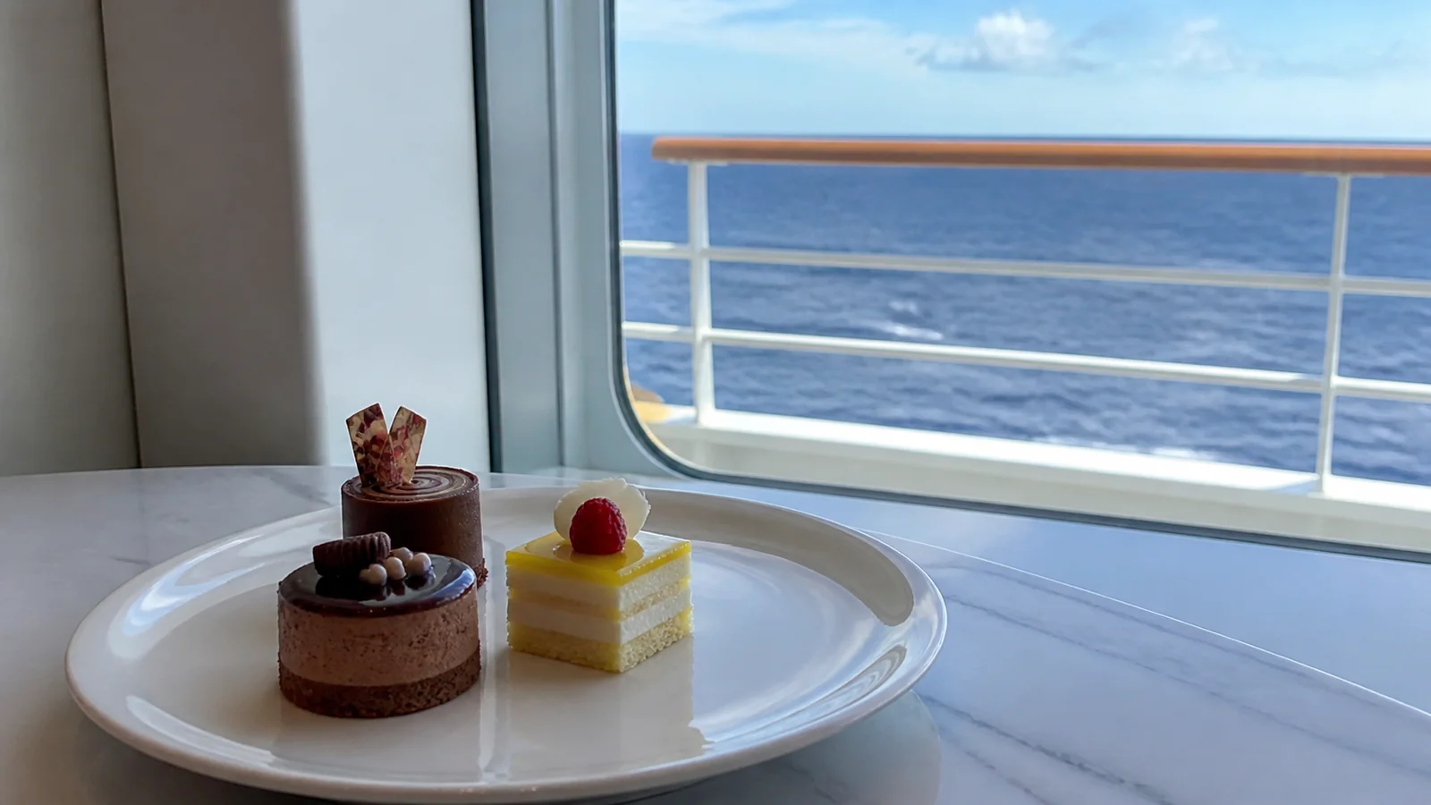 Small decorated desserts served beside an ocean-view window.