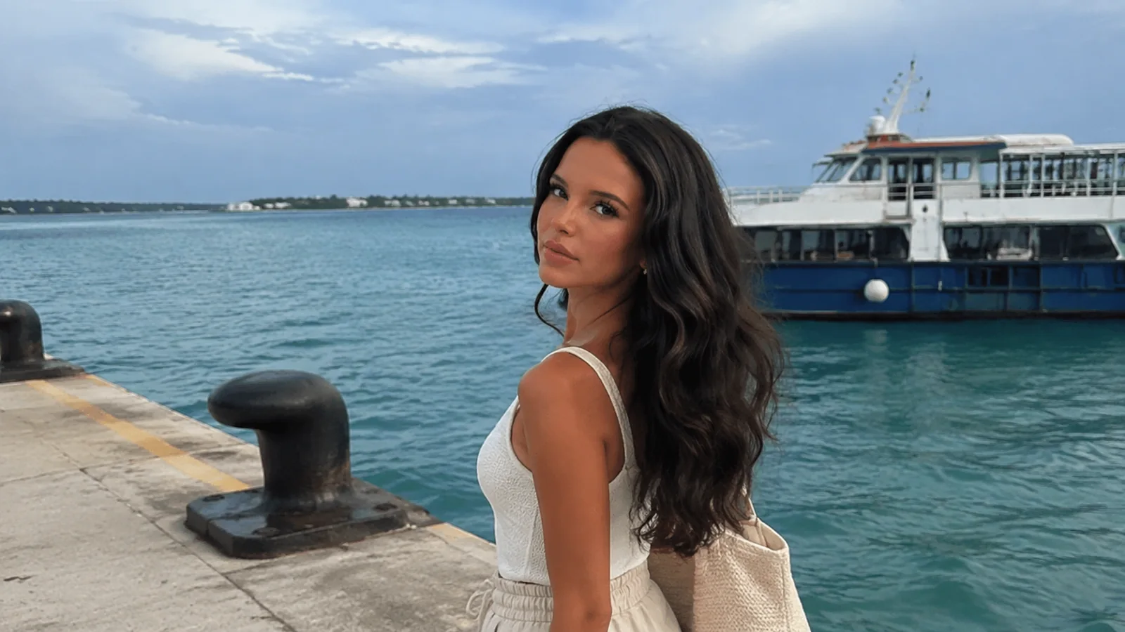 Woman standing beside a harbor bollard and passenger ferry.