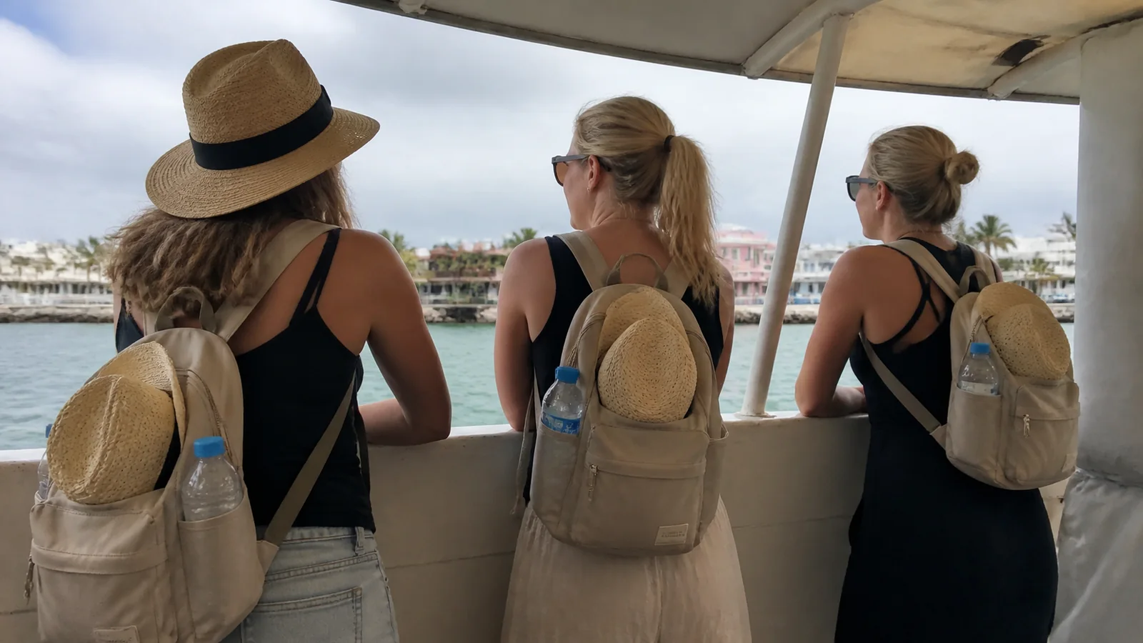 Travelers wearing daypacks with sunhats attached while riding a boat.