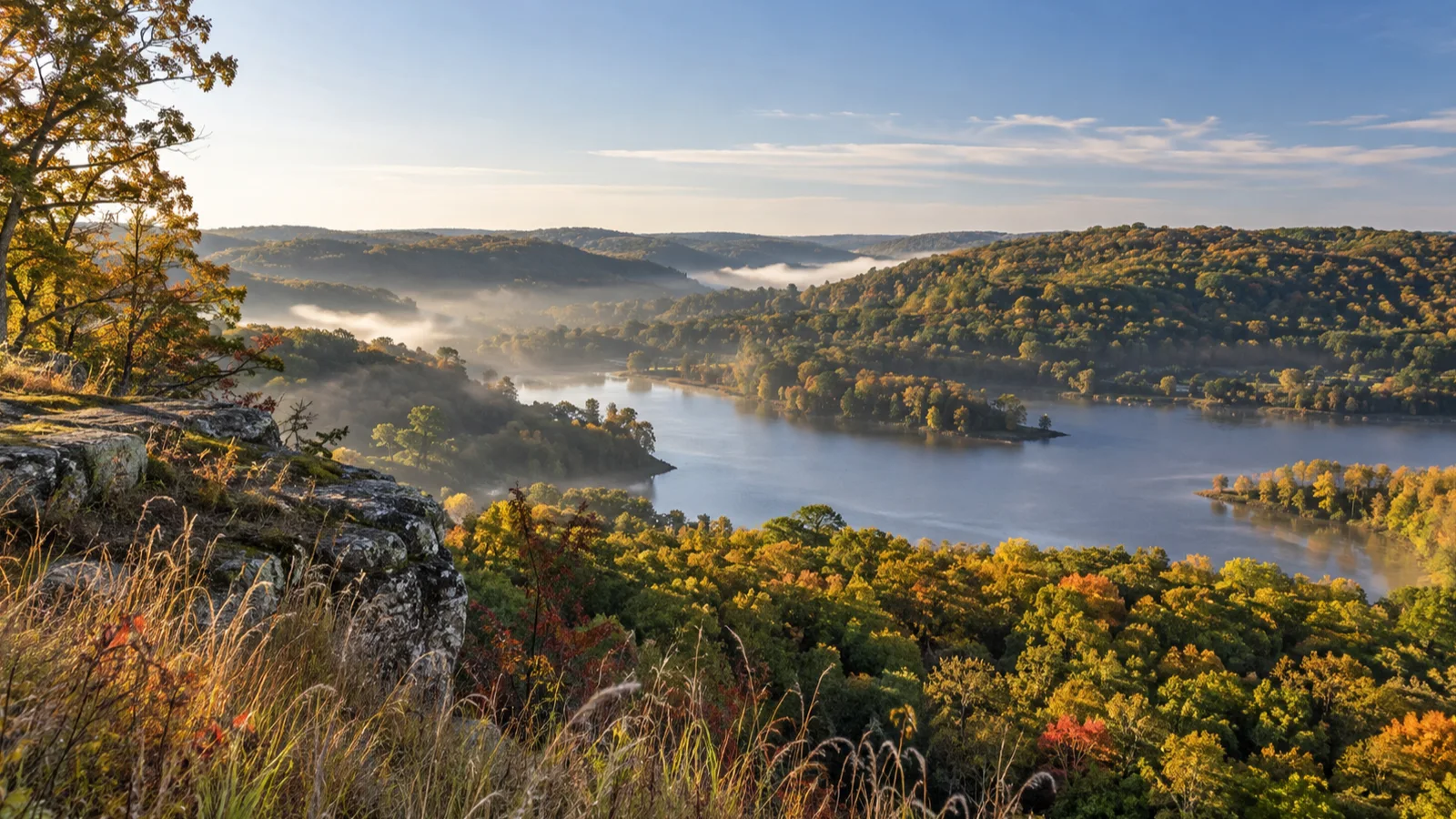A rocky bluff overlooks a calm lake and autumn woods in Governor Dodge State Park.