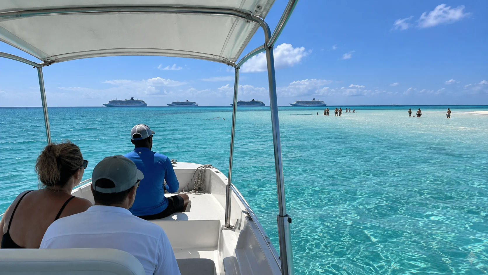 Excursion boat crossing turquoise water toward a shallow sandbar.